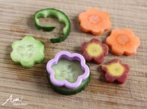 Pictures of various veggies being cut into shapes with a cookie cutter. 